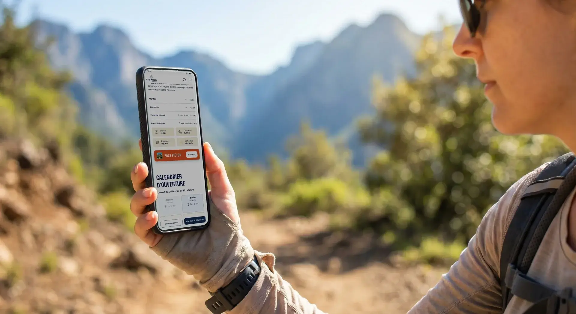 A person holds a smartphone displaying a hiking app with a 'Pedestrian Pass' button and an opening calendar, against a backdrop of sunny mountains.