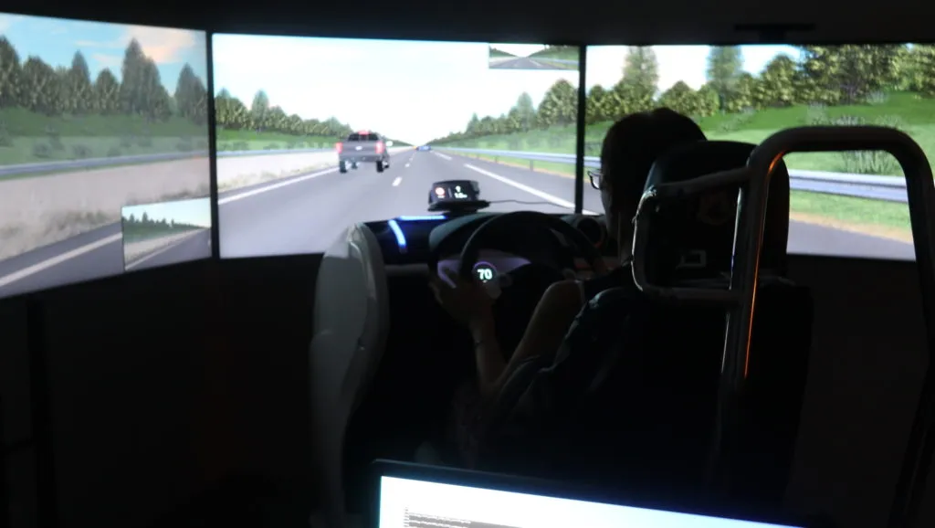 A person sitting in front of a car driving simulator