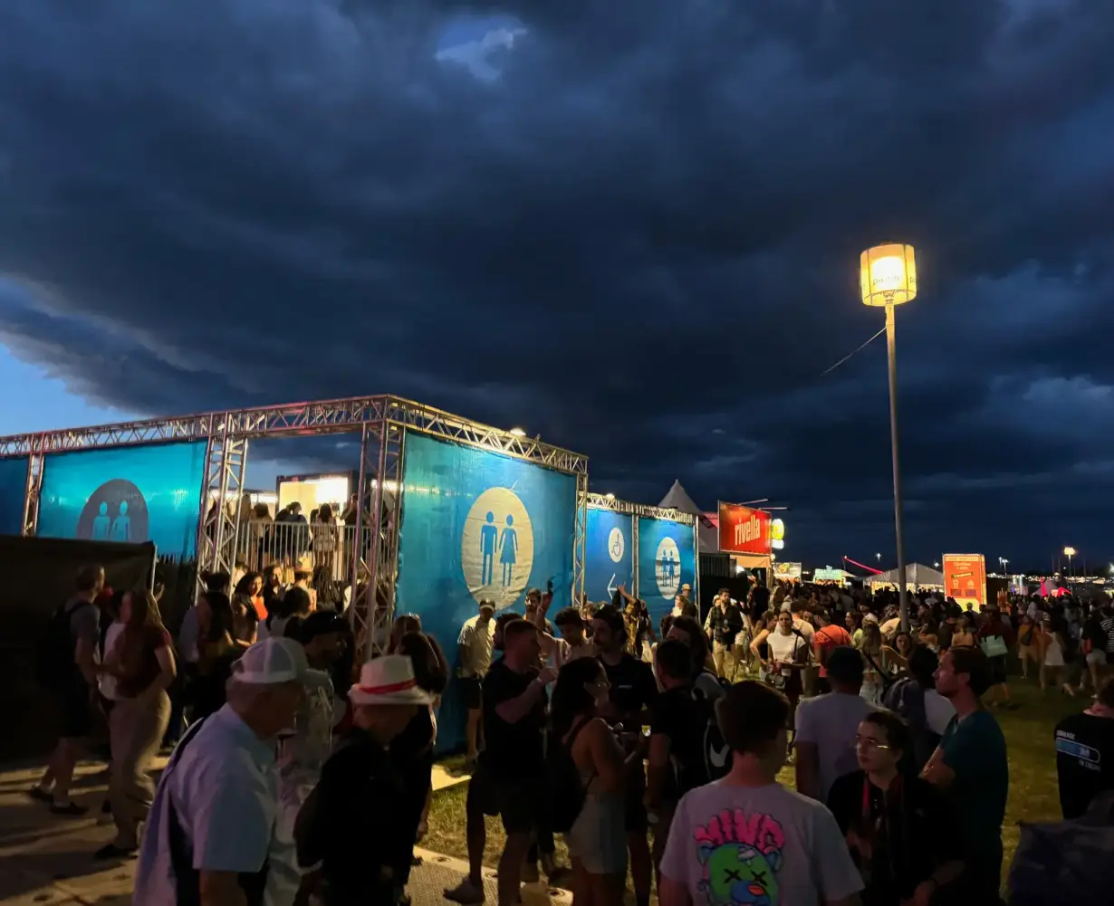 Blue toilet blocks at night with a crowd in stormy weather
