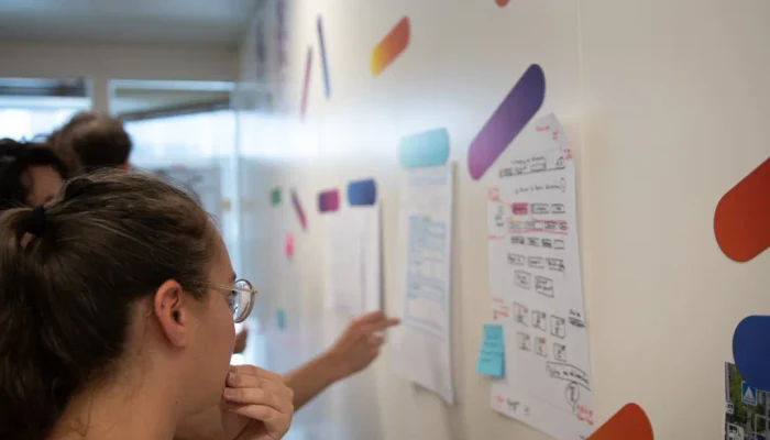 Co-design workshop in front of screen sketches displayed on a wall