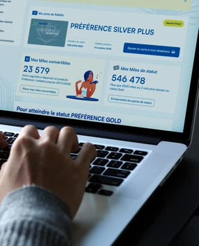 Des mains sur le clavier d'un ordinateur affichant l'espace client Air Caraïbes.
