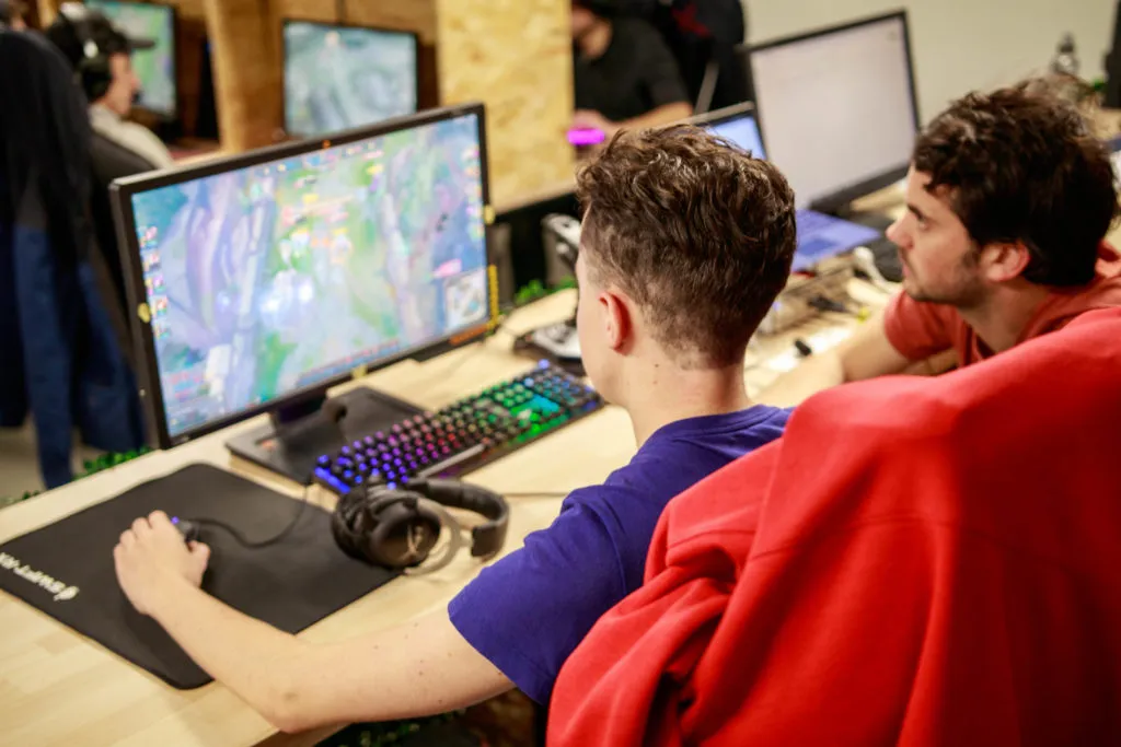 Esport: player seen from behind playing LoL, observed by an agency team member
