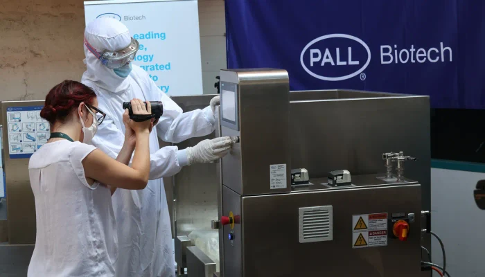 Field observation in a biotech workshop, with one person filming an operator in protective clothing next to industrial equipment