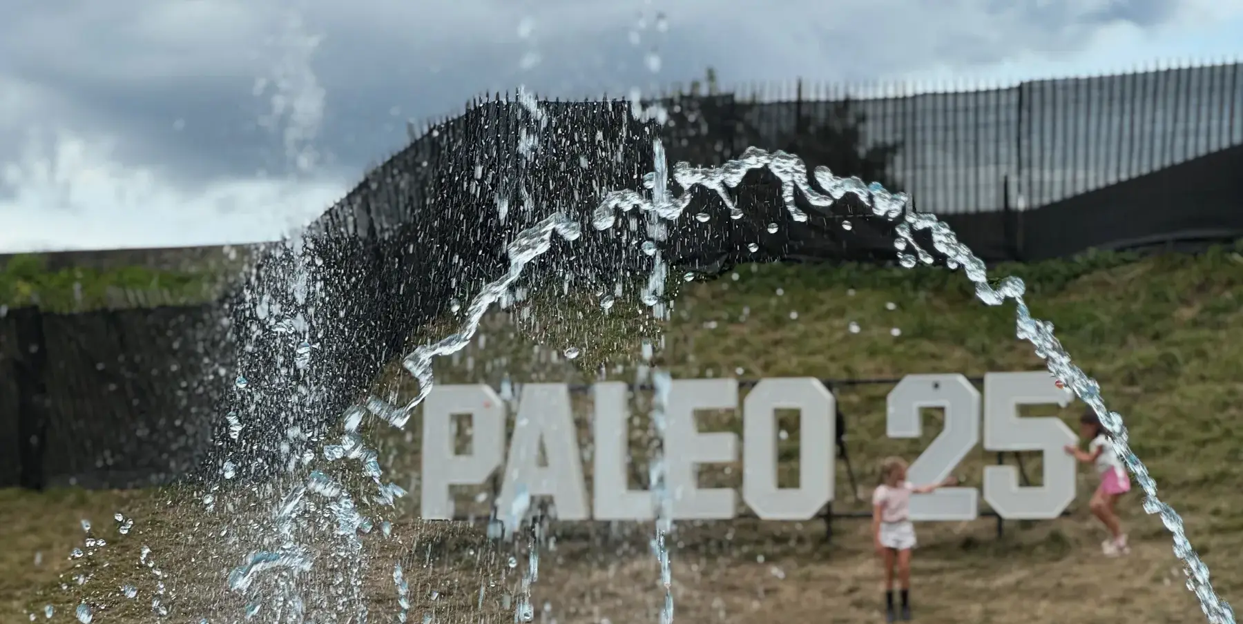 Paléo 25 fountain with letters on the hill and a crowd