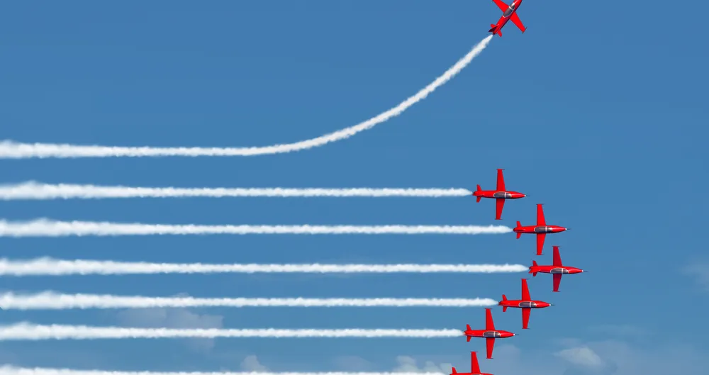 Formation d'avions rouges laissant des traînées blanches, l'un montant à l'écart