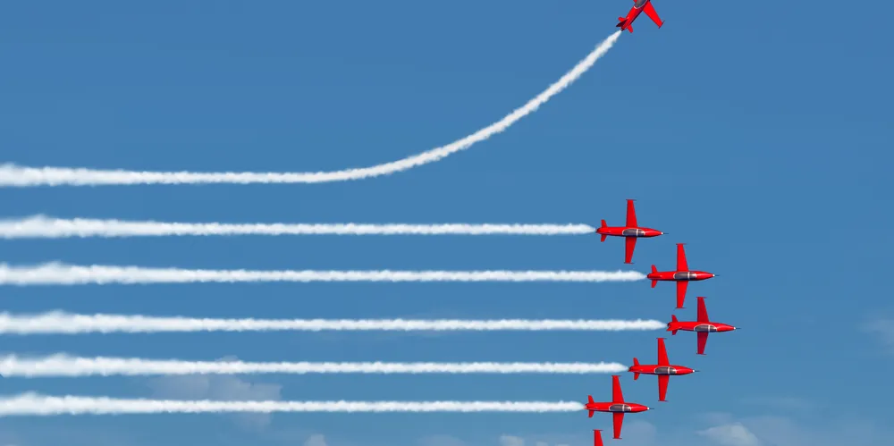 Formation d'avions rouges laissant des traînées blanches, l'un montant à l'écart