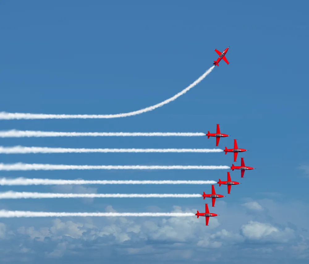 Formation d'avions rouges laissant des traînées blanches, l'un montant à l'écart