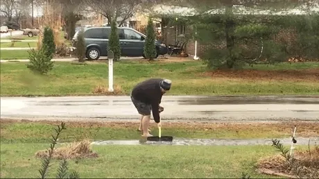 GIF d'une personne plantant un piquet dans une pelouse au bord d'une route