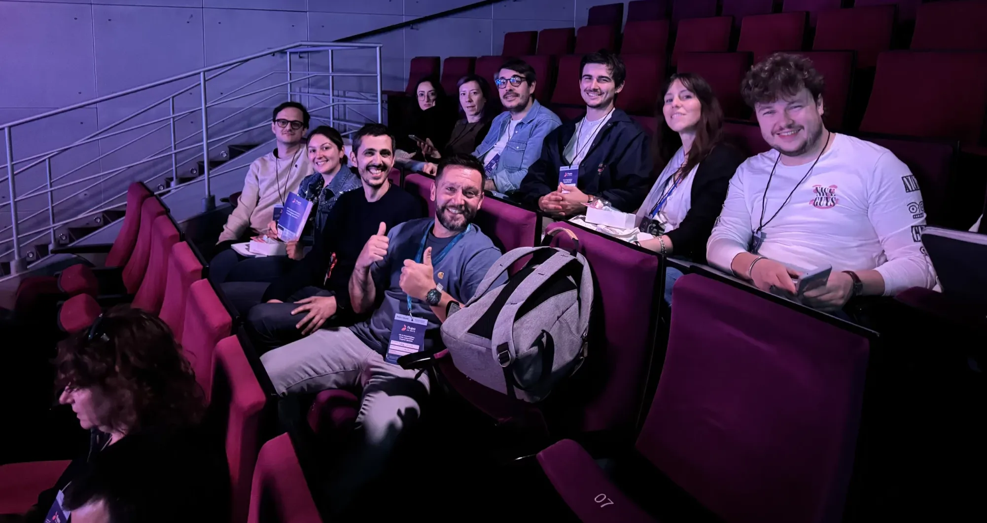 Groupe assis dans des fauteuils d'auditorium et regardant vers l'objectif