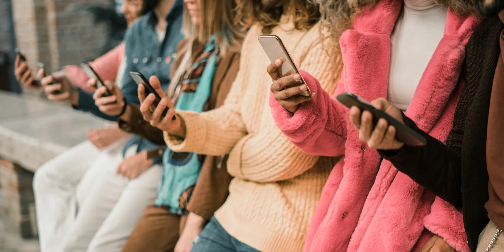 Groupe de personnes alignées, chacune tenant et consultant un téléphone