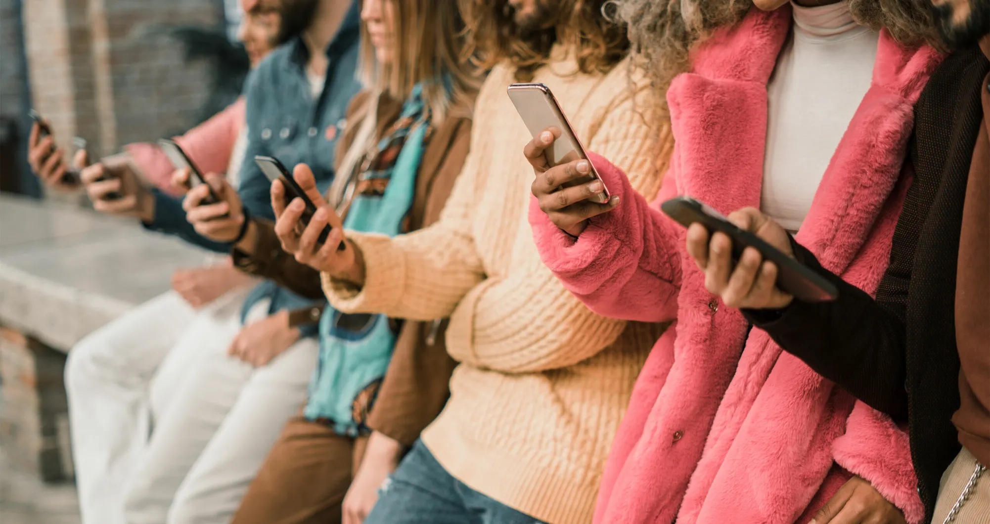 Groupe de personnes alignées, chacune tenant et consultant un téléphone