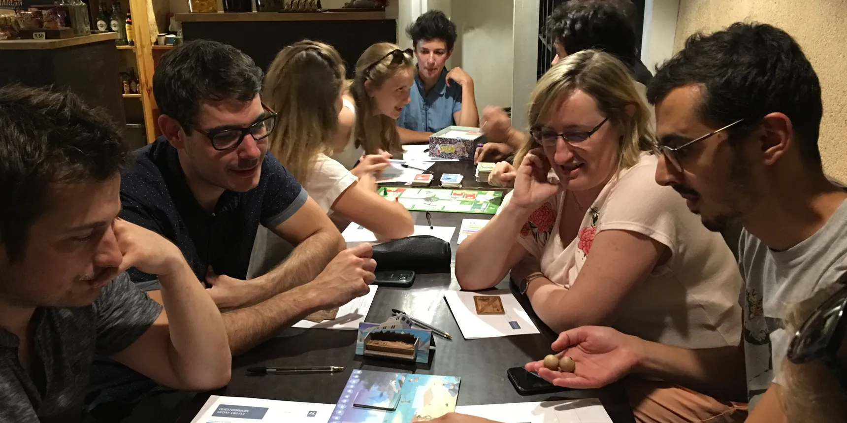 Groupe de personnes autour d'une table couverte de cartes et de plateaux de jeu