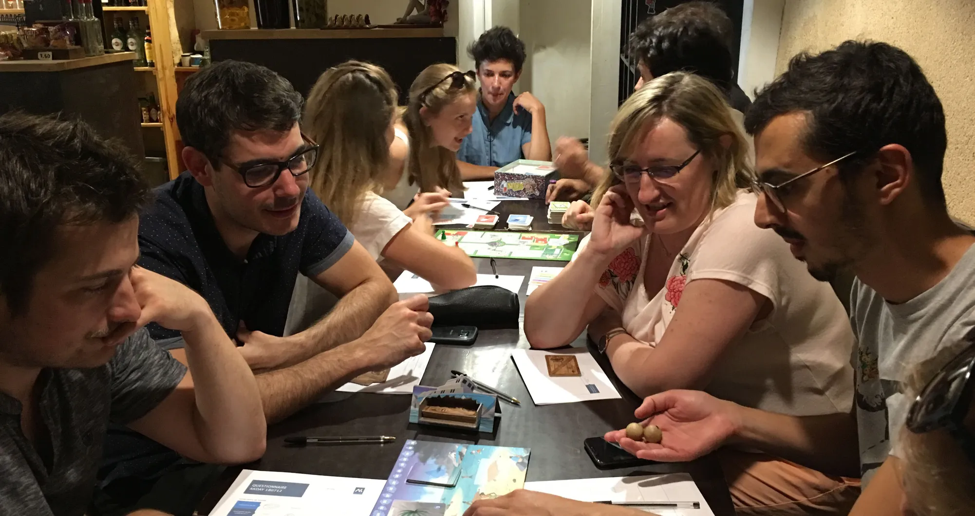 Groupe de personnes autour d'une table couverte de cartes et de plateaux de jeu