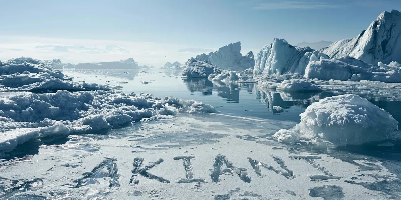 Le mot AKIANI inscrit dans la glace au pied d'icebergs, paysage polaire