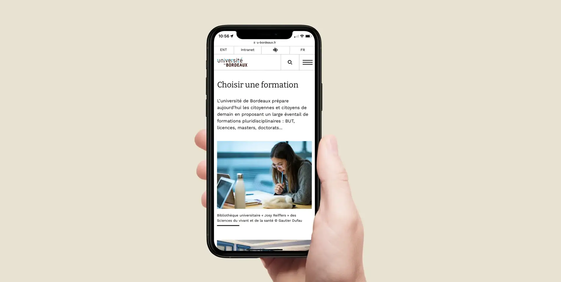 Main tenant un smartphone affichant la page « Choisir une formation » et la photo d’une étudiante en bibliothèque