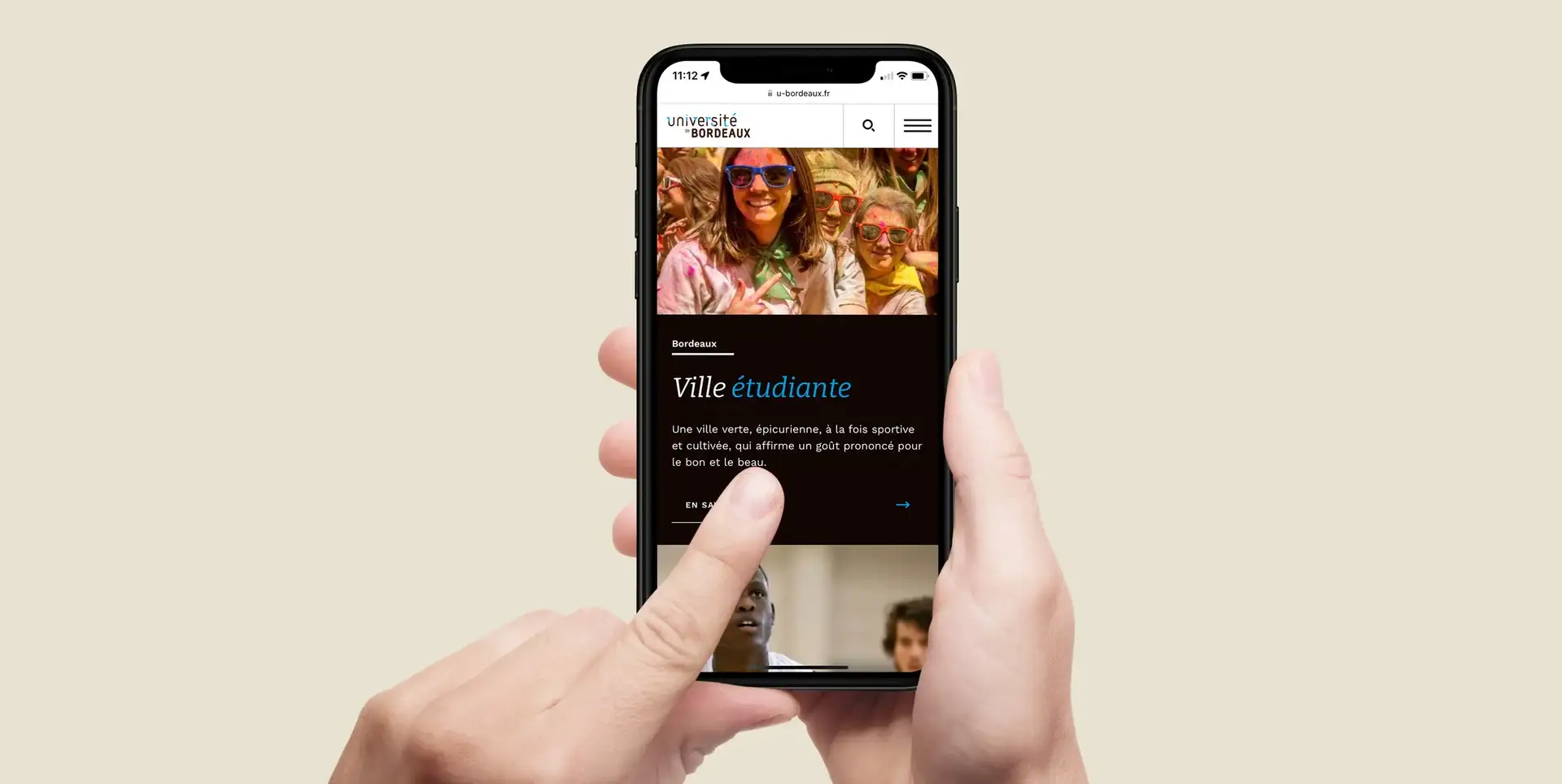 Mains tenant un smartphone affichant la page « Ville étudiante » et la photo d’un groupe portant des lunettes colorées