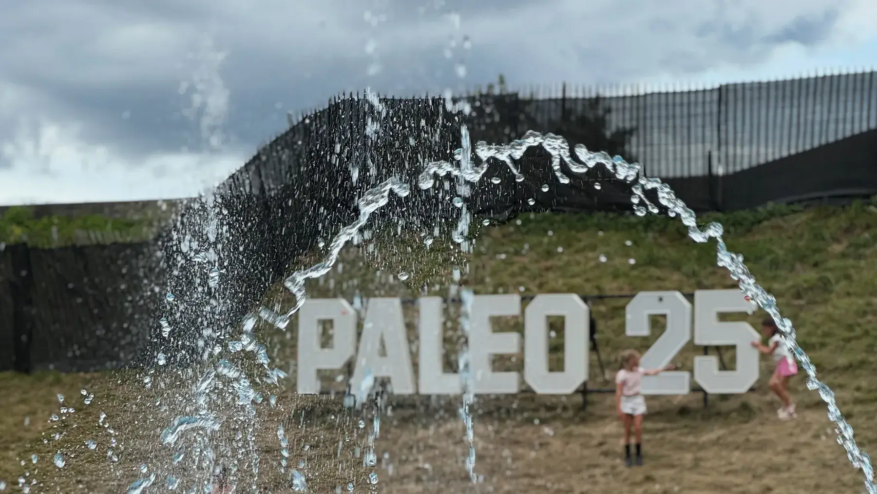 Paléo 25 fountain with letters on the hill and a crowd