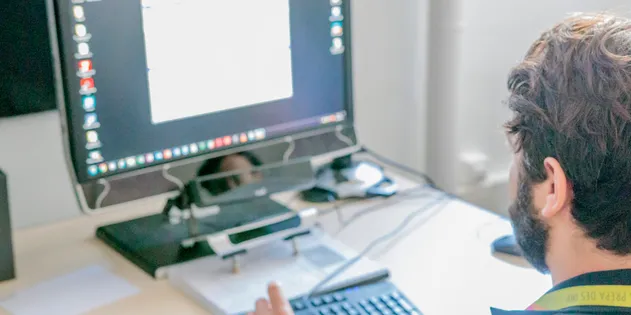 Personne assise devant un ordinateur dont l'écran affiche une fenêtre claire