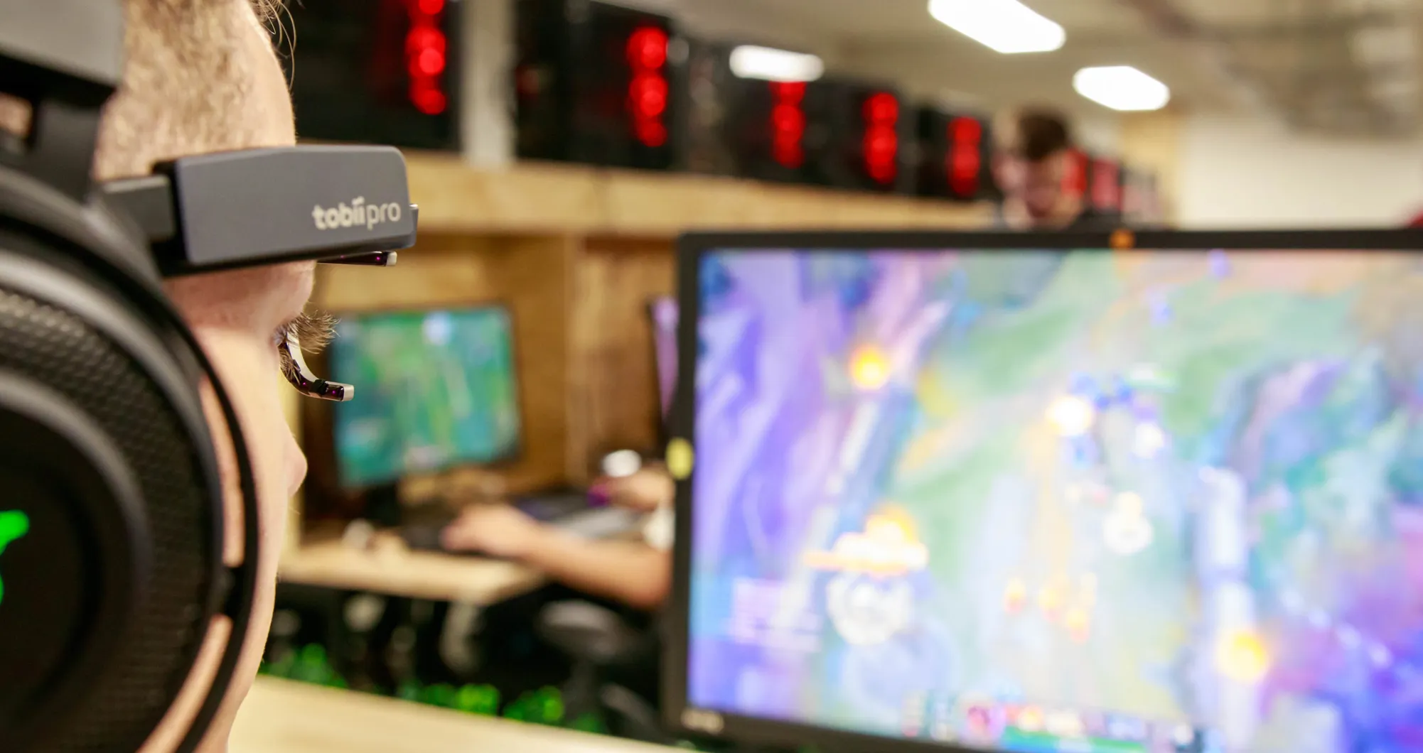 Person using a "tobii pro" eye tracker in front of several gaming screens