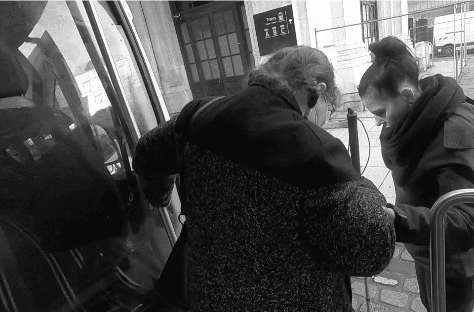 Photo of a person with a visual impairment being helped to get off a vehicle as part of the study of travellers with disabilities