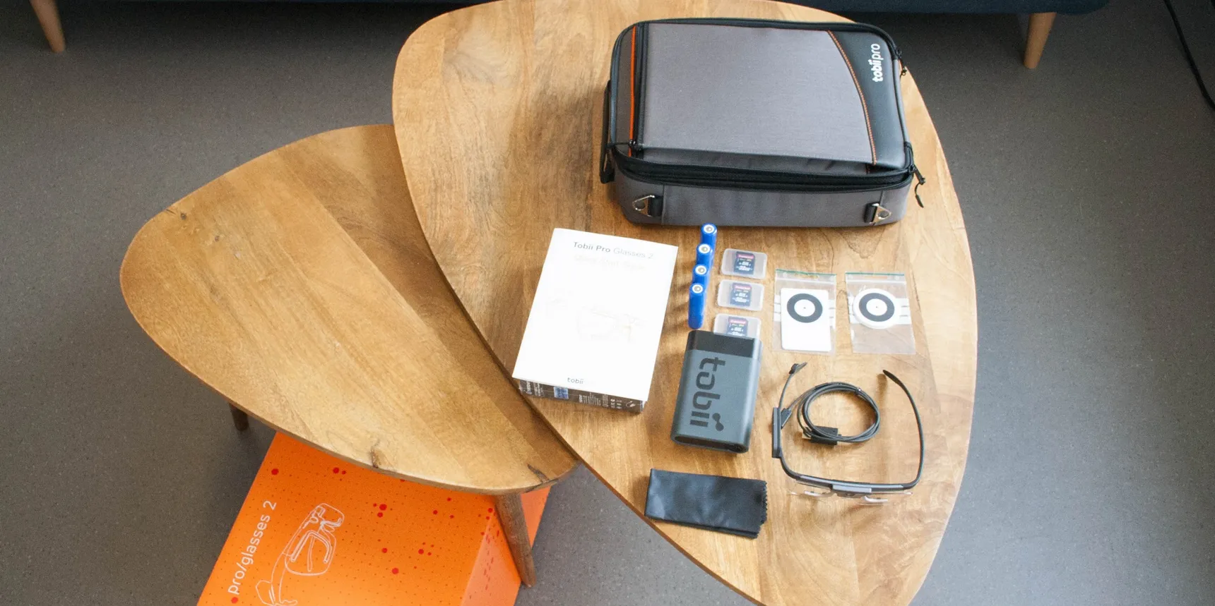 Coffee table covered with an open case, documents, devices, and cables