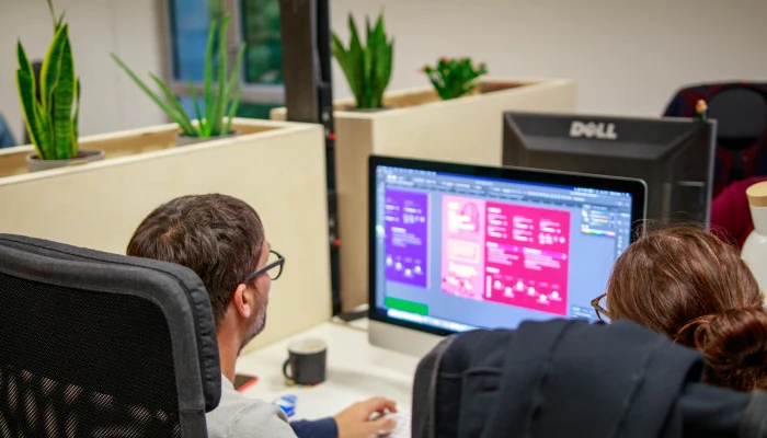 Two designers working on a graphic identity direction shown on screen