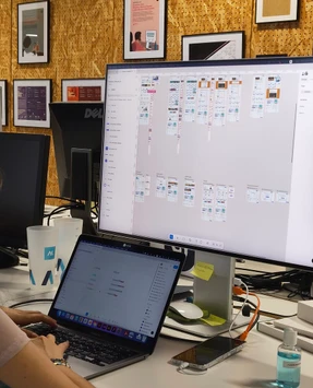 Un designer travaille sur des maquettes UI dans un bureau avec un mur en bois.