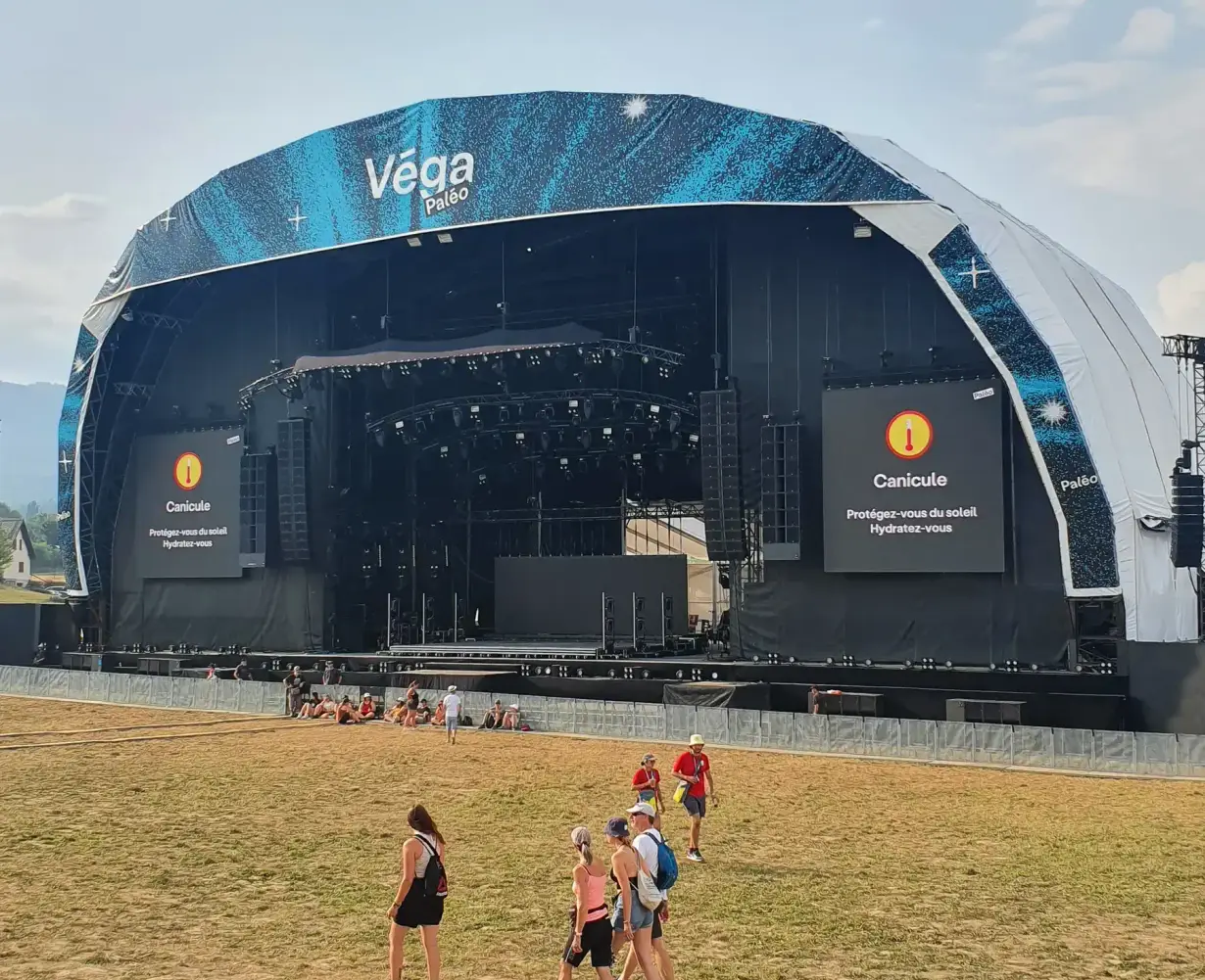 Véga stage with a blue sphere and festival-goers on the grass