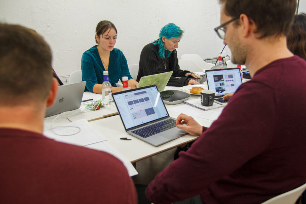 L'équipe Akiani, réunie autour d'une table, est concentrée sur leurs oridinateurs à l'occasion de la deuxième journée de formation sur l'écoconception.