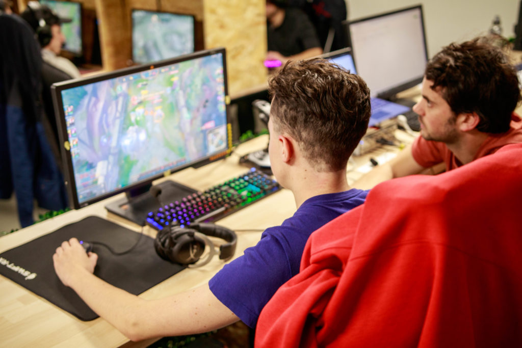 Esport : joueur de dos en train de jouer à LOL observé par un membre de l'agence