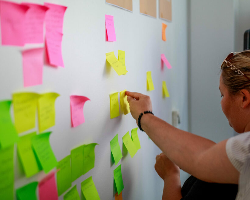 Deux personnes en atelier en train de positionner des post-it au mur
