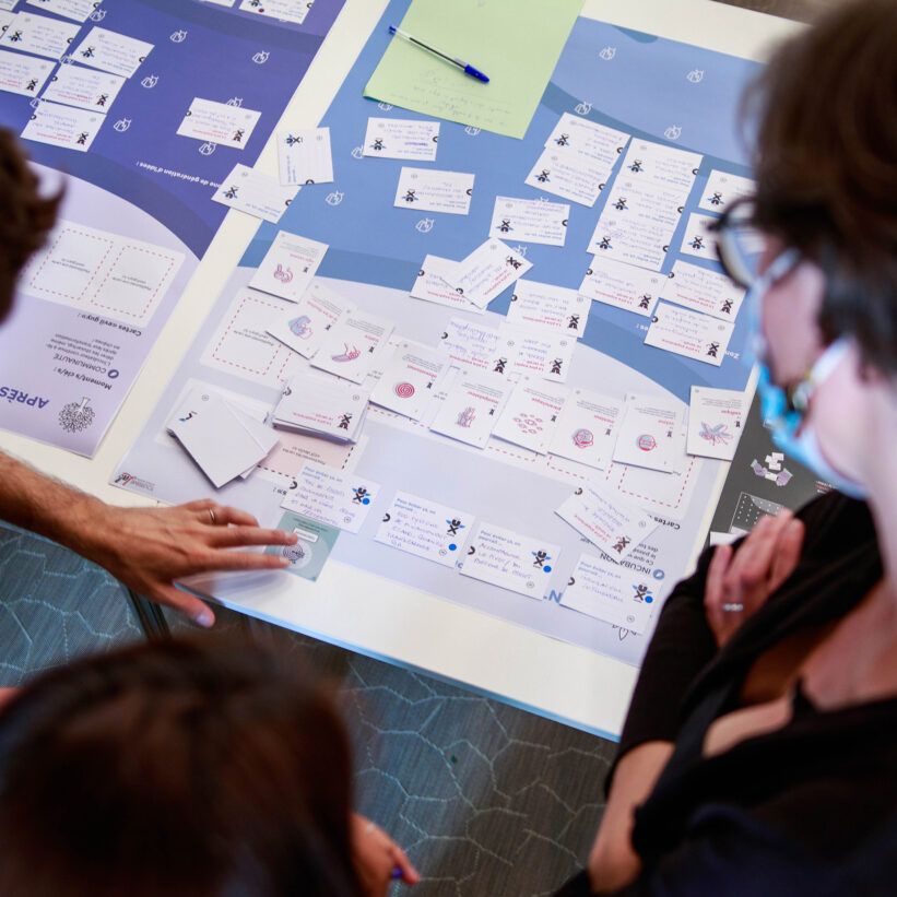 Deux membres d'un groupe de travail positionnent les cartes sur le plateau de la phase travaillée